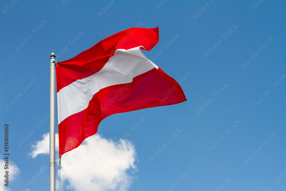 Flag of Austria waving in the wind on flagpole against the sky with clouds on sunny day, close-up - obrazy, fototapety, plakaty 