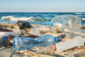 spilled garbage on the beach of the big city. empty used dirty plastic bottles. dirty sea sandy shor