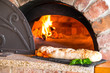 Rustic home-made stuffed pizza roll (Italian: rotolo di pizza farcito) baked in a wood fired brick oven and served on a black stone slate table.  