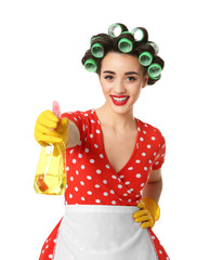 Poster - Funny young housewife with hair rollers holding detergent on white background