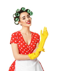 Poster - Funny young housewife with hair rollers putting on rubber gloves against white background