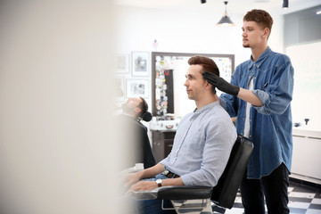 Professional barber working with client in hairdressing salon. Hipster fashion