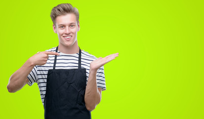 Poster - Young handsome blond man wearing apron very happy pointing with hand and finger