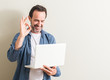 © Krakenimages.com - Senior man using laptop computer doing ok sign with fingers, excellent symbol