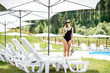 © rh2010 - Young woman in black swimsuit standing with cocktail at the swimming pool area during summer vacations
