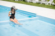 © rh2010 - Young woman in black swimsuit and sun hat relaxing with cocktail in the swimming pool outdoors
