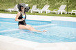 © rh2010 - Young woman in black swimsuit and sun hat relaxing with cocktail in the swimming pool outdoors