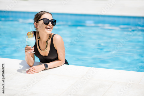 Fotografía Portrait of a beautiful woman in black swimsuit relaxing with cocktail at the sw
