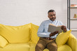 © LIGHTFIELD STUDIOS - senior african american man sitting on sofa and reading book