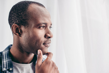 close-up portrait of pensive african american man with hand on chin looking away