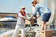 © pressmaster - Senior yachtsman and his assistant loading boxes on boat before sailing trip on summer weekend