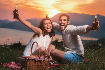 Portrait of young couple having good times on a picnic date, behind them is a beautiful sunset over Boka Bay