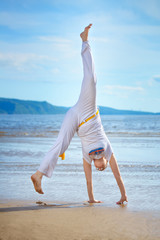 Woman practicing capoeira on the beach. The woman does the fighting element of capoeira.