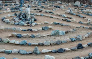 Traditional natural stone walking labyrinth maze made for contemplation and worship, created with rocks in shades of blue and turquoise.