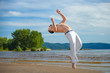 Man practicing capoeira on the beach. The man does the fighting element of capoeira.