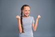 © Viacheslav Yakobchuk - Great achievement. Elated teenage girl doing fist pumps and smiling happily while posing isolated on a blue-grey background
