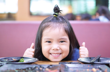 Wall Mural - Asian children cute hungry or kid girl smile enjoy eating and appetizing with eat rice or food a lot and completely for good healthy on table in delicious restaurant with thumb up for like or great