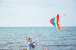 © ruslanshug - active healthy kid with flying colorful kite on sky and sea background outdoor