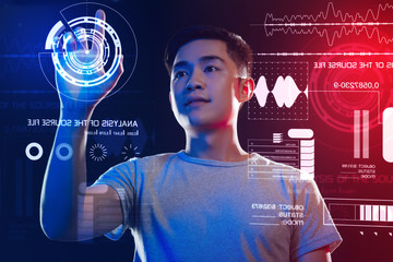 Careful worker. Calm clever software developer thoughtfully touching the round icon on the transparent screen while working at the program