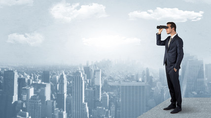 Wall Mural - businessman looking forward to a city with binoculars from skyscraper concept