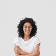 © wayhome.studio  - Glad female student has Afro hairstyle, broad smile, keeps hands crossed, wears glasses, happy to spend evening with family, wears t shirt in one tone with background. People and emotions concept