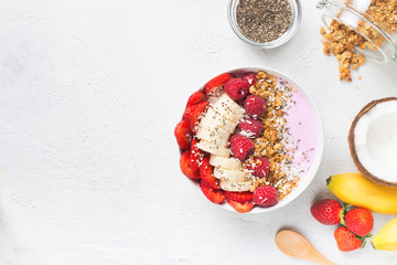 Pink smoothie in bowl with banana, strawberry and raspberry