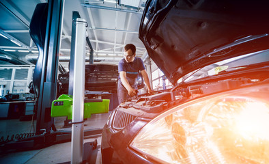 Wall Mural - Worker checks and adjusts the headlights of a car's lighting system