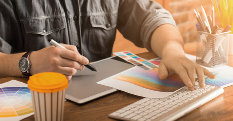 Young creative artist of web design in hat with graphic tablet in modern loft office