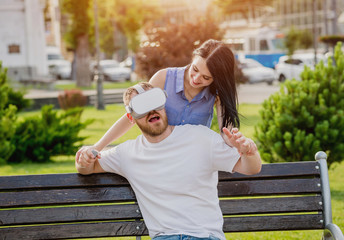 A young couple plays a game using virtual reality glasses on the street.