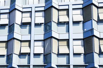 Front facade of a contemporary blue office building with arched windows