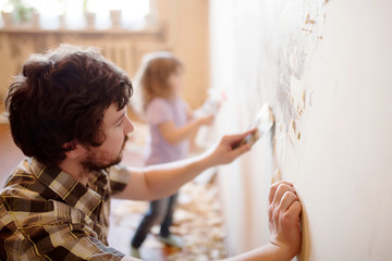 Father and daughter repairing wall, holding putty knife