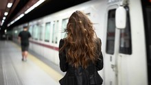 Attractive Woman In An Underground Subway Station Checking Her Phone As A Train Arrives In Slow Motion