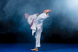 Pre-teen boy doing karate on a black background with smoke