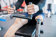 Mid section close up of unrecognizable muscular man with prosthetic leg using weight machines while working out  in gym, copy space