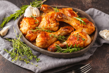 Wall Mural - Grilled spicy chicken legs baked with garlic, rosemary and thyme on dark background.