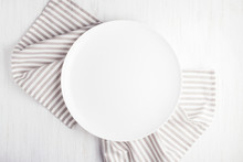 Empty White Circle Plate On Wooden Table With Linen Napkin. Overhead View.