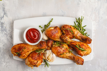 Wall Mural - Grilled spicy chicken legs baked with garlic, rosemary and thyme on white background.