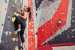 Rear view of sportwoman climber moving up on steep rock, climbing on artificial wall indoors. Extreme sports and bouldering concept.