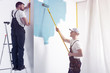© Photographee.eu - Man with roller painting white wall on blue while finishing interior
