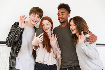 Wall Mural - Happy group of friends students talking by mobile phone waving.