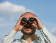 © APHOTOSTUDIO - bearded man detective looks through binoculars in the distance and watches.