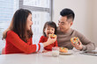 © makistock - Happy young family with children enjoying breakfast in a white sunny dining room with a big garden view window