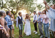 © Halfpoint - Bride, groom and guests at wedding reception outside in the backyard.