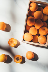 Wall Mural - flat lay with ripe apricots in wooden box on light marble surface