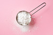 Powder sugar on pink background, from above