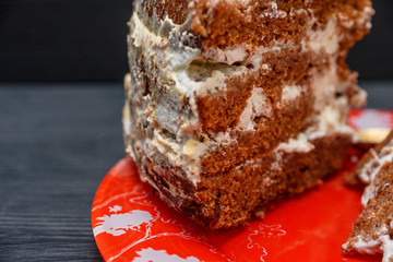 sour cream cake with cream on a dark wooden background