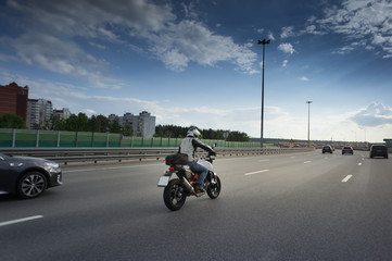 Back view of motorcycle driver driving in beautiful sunset. Clouds on the sky. Sound or acoustic barrier