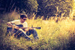 Junger Mann sitzt in der Wiese und spielt Gitarre