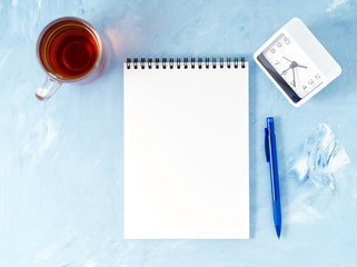 Wall Mural - Top view of modern bright blue office desktop with notepad, clock, flower succulent. Mock up, empty space