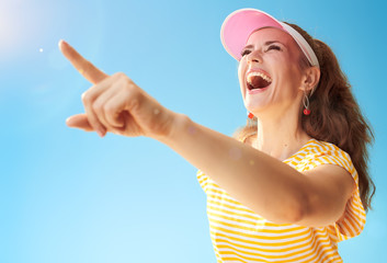 happy active woman against blue sky pointing at something